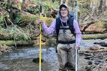 Bridget Reheard standing in a stream with hiking gear 