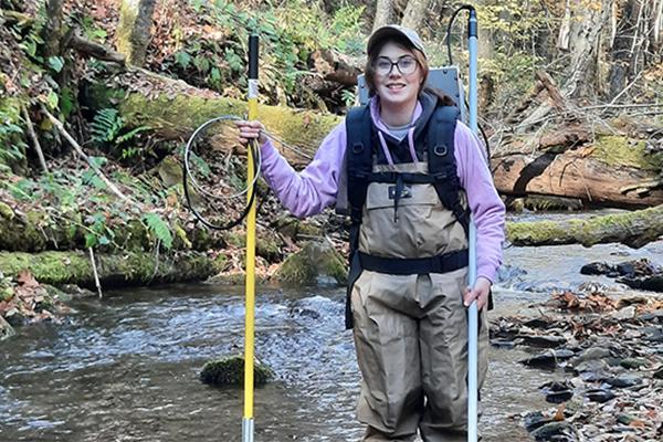 Bridget Reheard standing in a stream with hiking gear 
